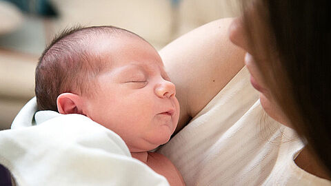 Foto van een pasgeboren baby in de armen van zijn moeder